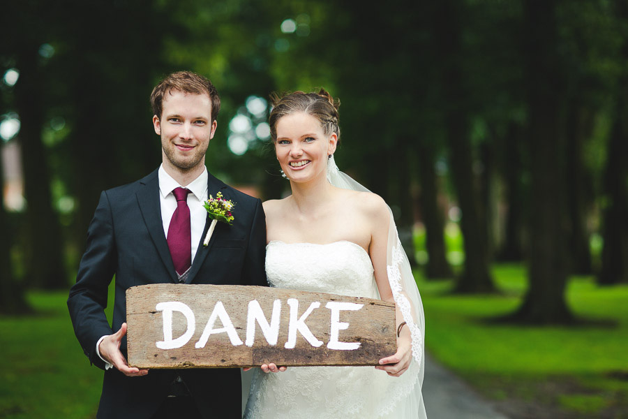 Brautpaar hält ein selbstgemachtes Holzschild mit Danke