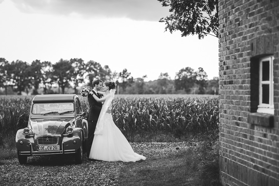 Eine sogenannte Ente als Oldtimer Hochzeitsauto daneben das Brautpaar am knutschen