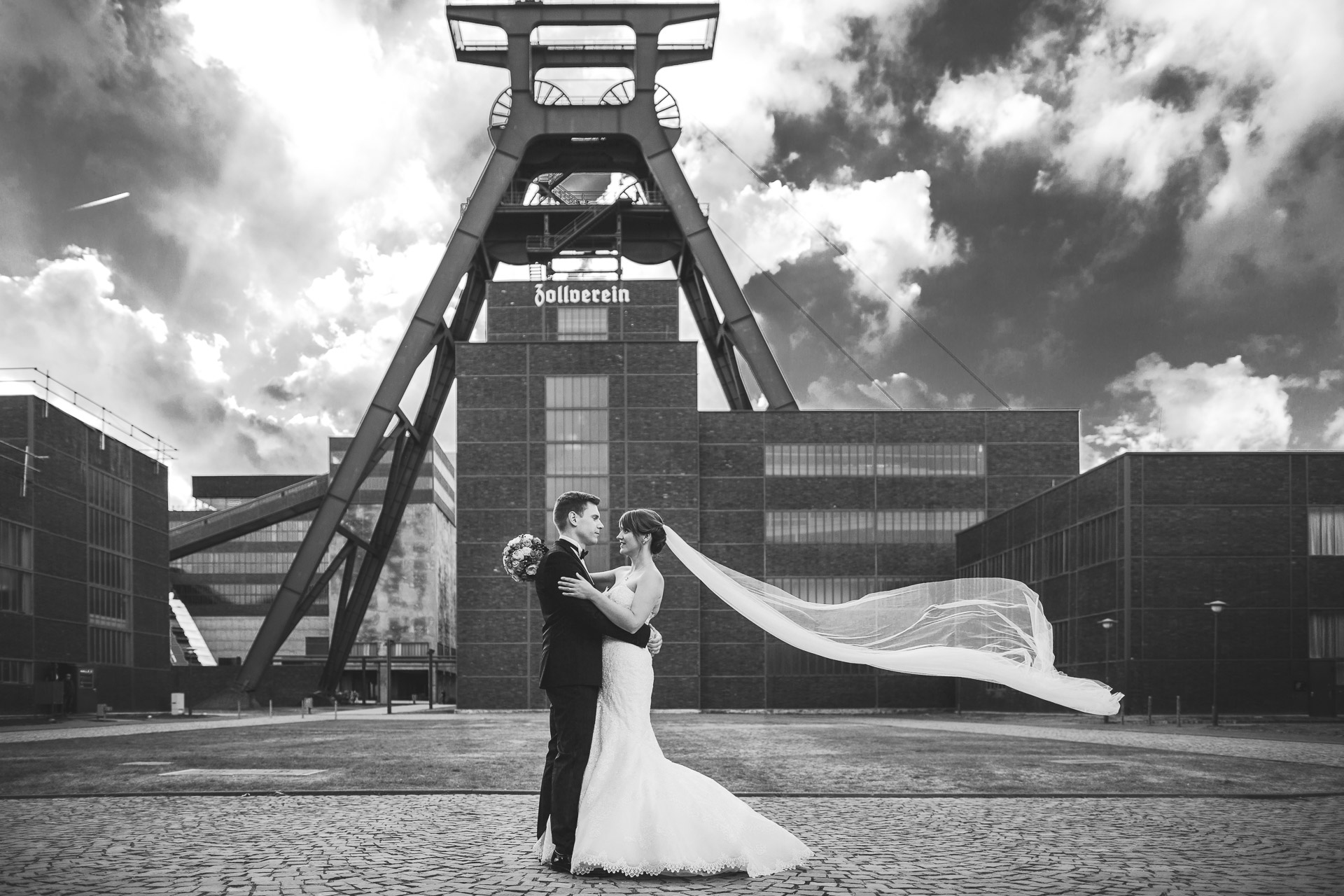 geiles Hochzeitsfoto auf der Zeche Zollverein in Essen. Schleier der Braut fliegt cool in der Luft.