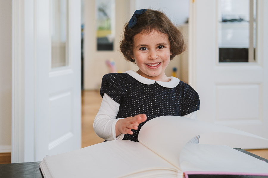 Glückliches Mädchen blättert Familienalbum durch – natürliche Weihnachtsfotos