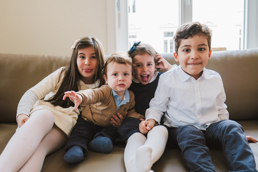 Vier Kinder machen ausgelassen Quatsch auf dem Sofa – fröhliche Weihnachts-Familienfotos